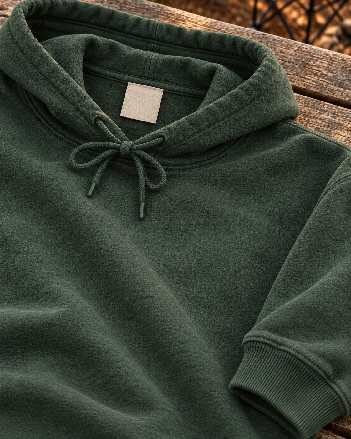 Forest green hoodie hood and drawstrings on a wooden bench