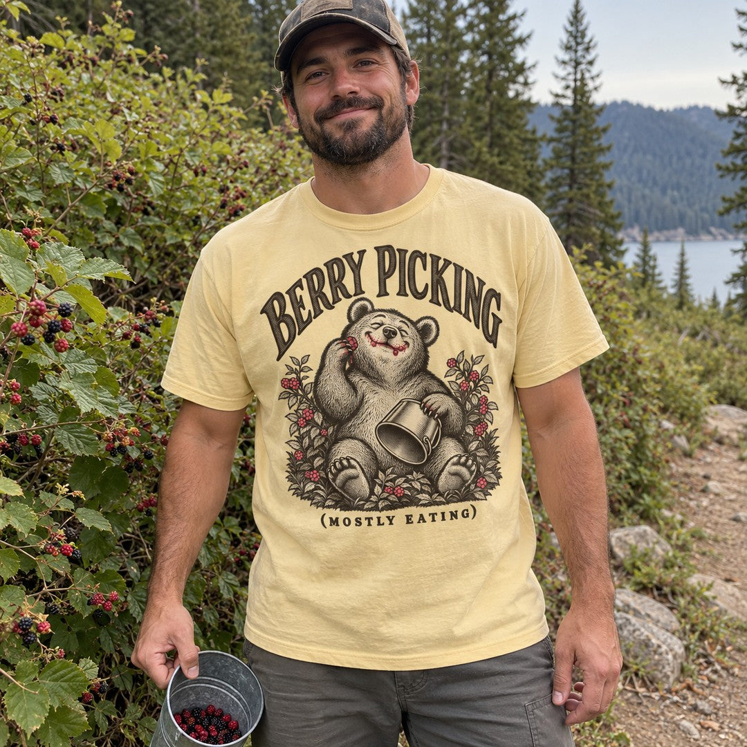 Man wearing the Berry Picking (Mostly Eating) bear T-shirt by wild berry bushes