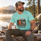 Man wearing the Coffee Tastes Better at Camp T-shirt at a lakeside campsite