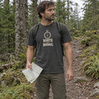 Man wearing the North of Normal T-shirt on a forest trail holding a paper map