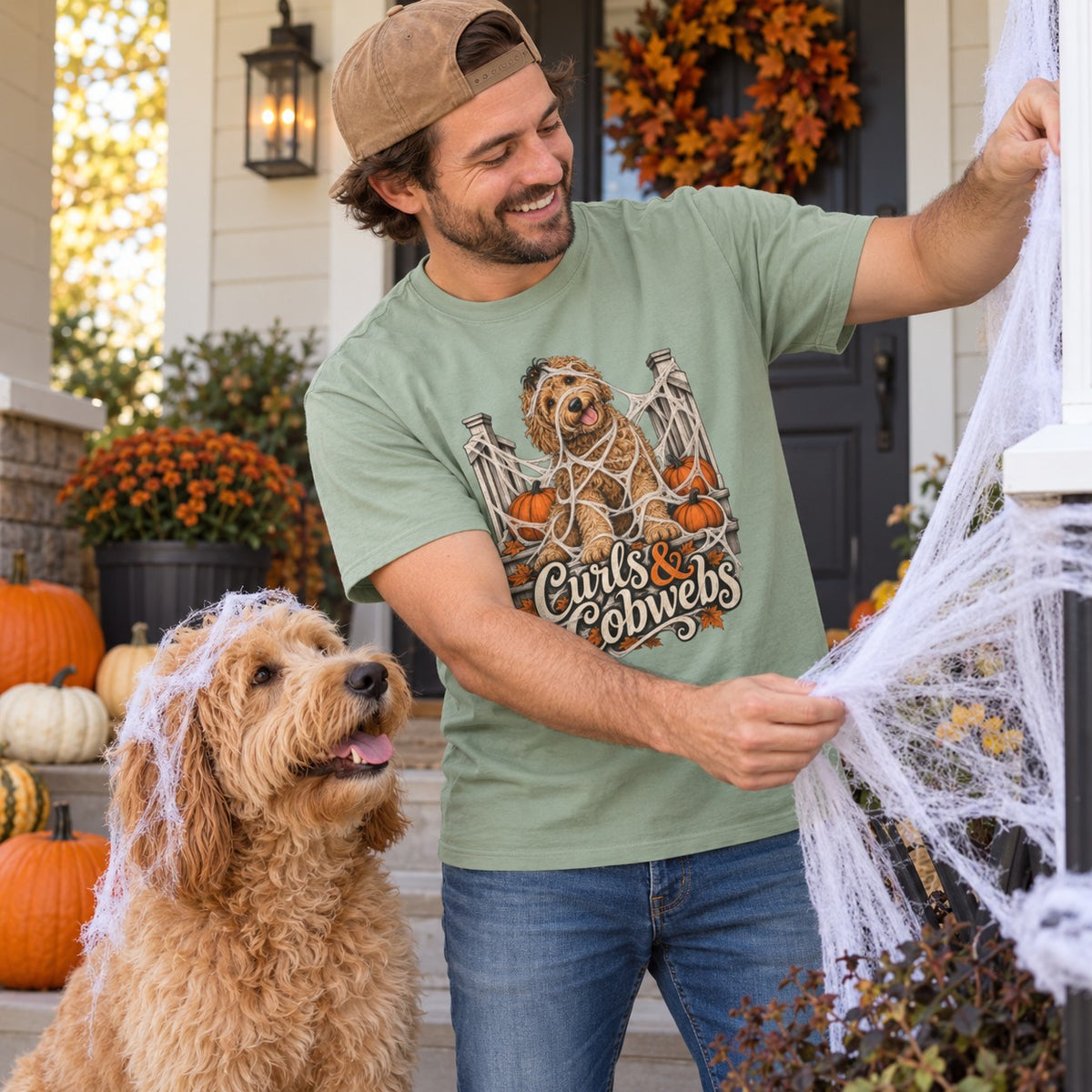Man wearing the Curls & Cobwebs T-Shirt decorating with his labradoodle
