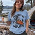 Woman wearing the Do Not Disturb Until Spring bear T-shirt at a snowy campsite