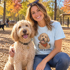 Woman wearing the Fluent in Doodle T-shirt with her labradoodle at a dog park