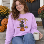Woman wearing the orchid Official Broom Inspector sweatshirt on her front porch with pumpkins