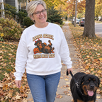 Woman wearing the white Looks Scary, Wants Belly Rubs sweatshirt walking her Rottweiler on a fall sidewalk