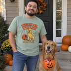 Man wearing the sage Trick or Treat (Mostly Treat) t-shirt on a pumpkin porch with his golden retriever
