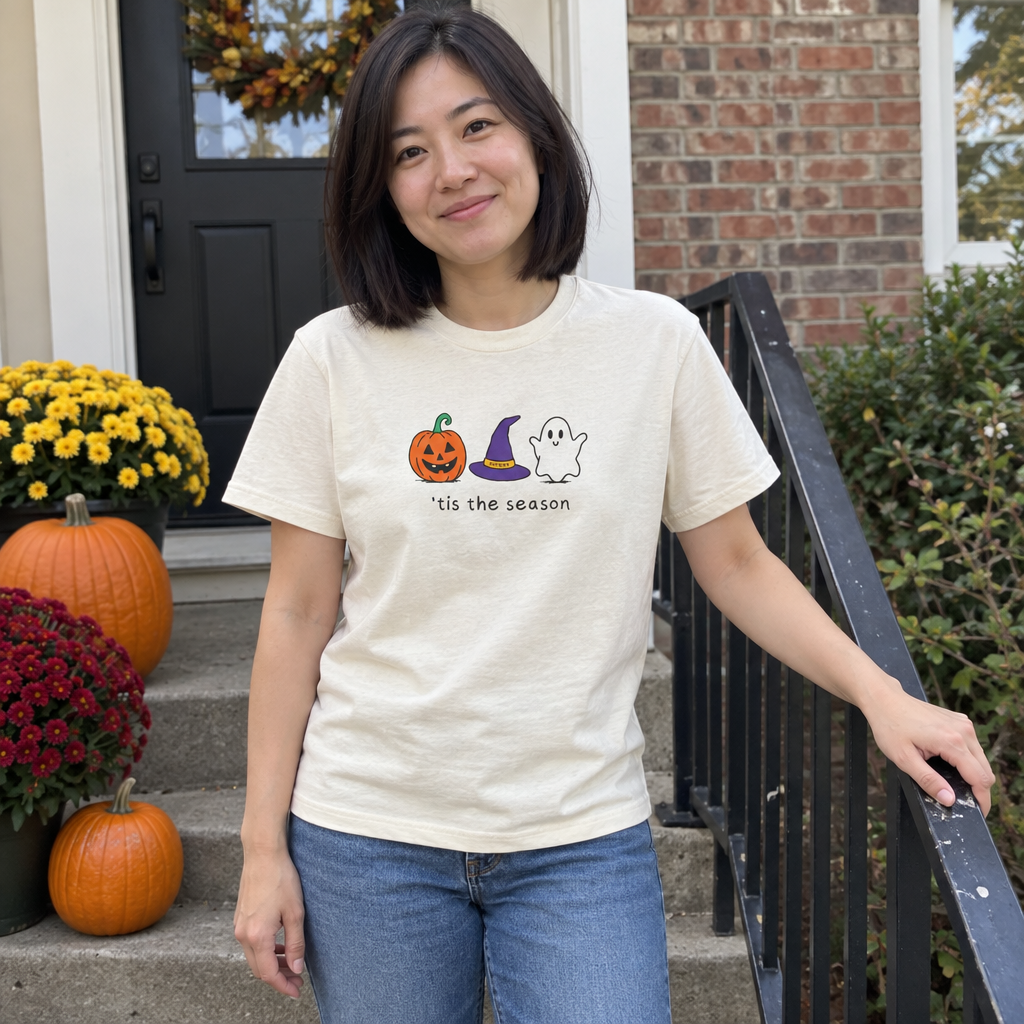 Woman wearing the Ivory Tis the Season t-shirt on a front porch with pumpkins
