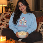 Woman wearing the light blue Cute and Creepy sweatshirt on the couch with popcorn