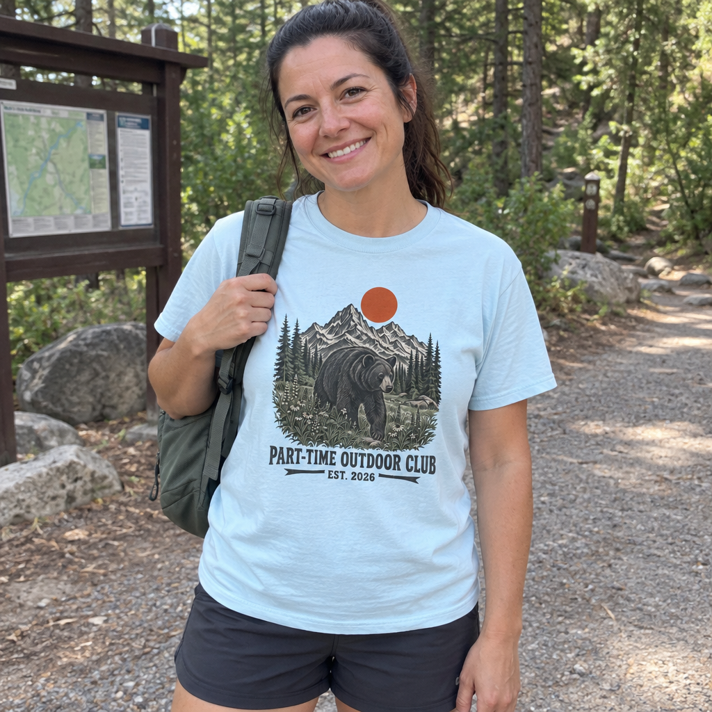 Woman wearing the light blue Outdoor Club Bear t-shirt at a forest trailhead