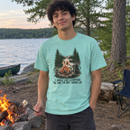 Man wearing the mint I Smell Like Campfire and I'm Not Sorry t-shirt by a lakeside campfire