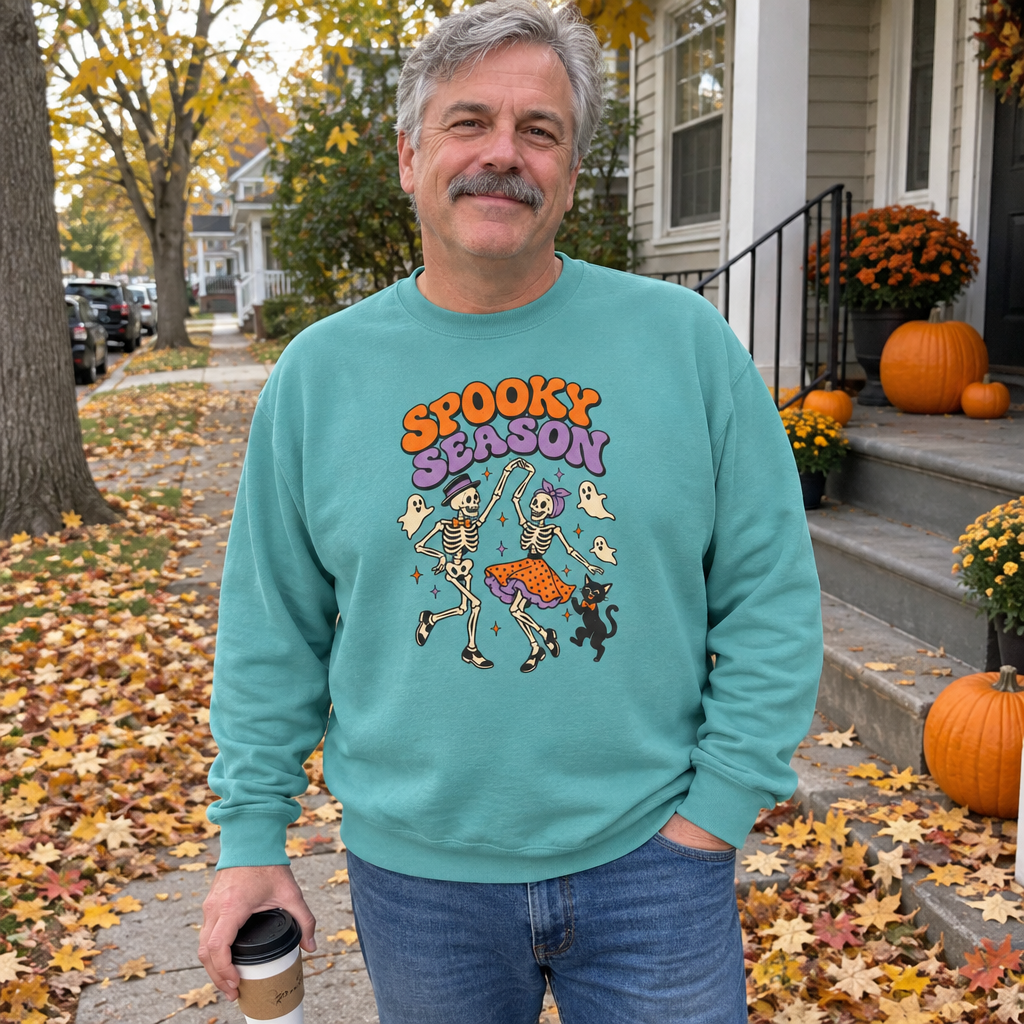 Man wearing the seafoam Spooky Season Dancing Skeletons sweatshirt on a fall leaves sidewalk
