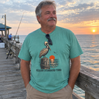 Man wearing the seafoam Pelican Standard Time t-shirt on a fishing pier at sunset