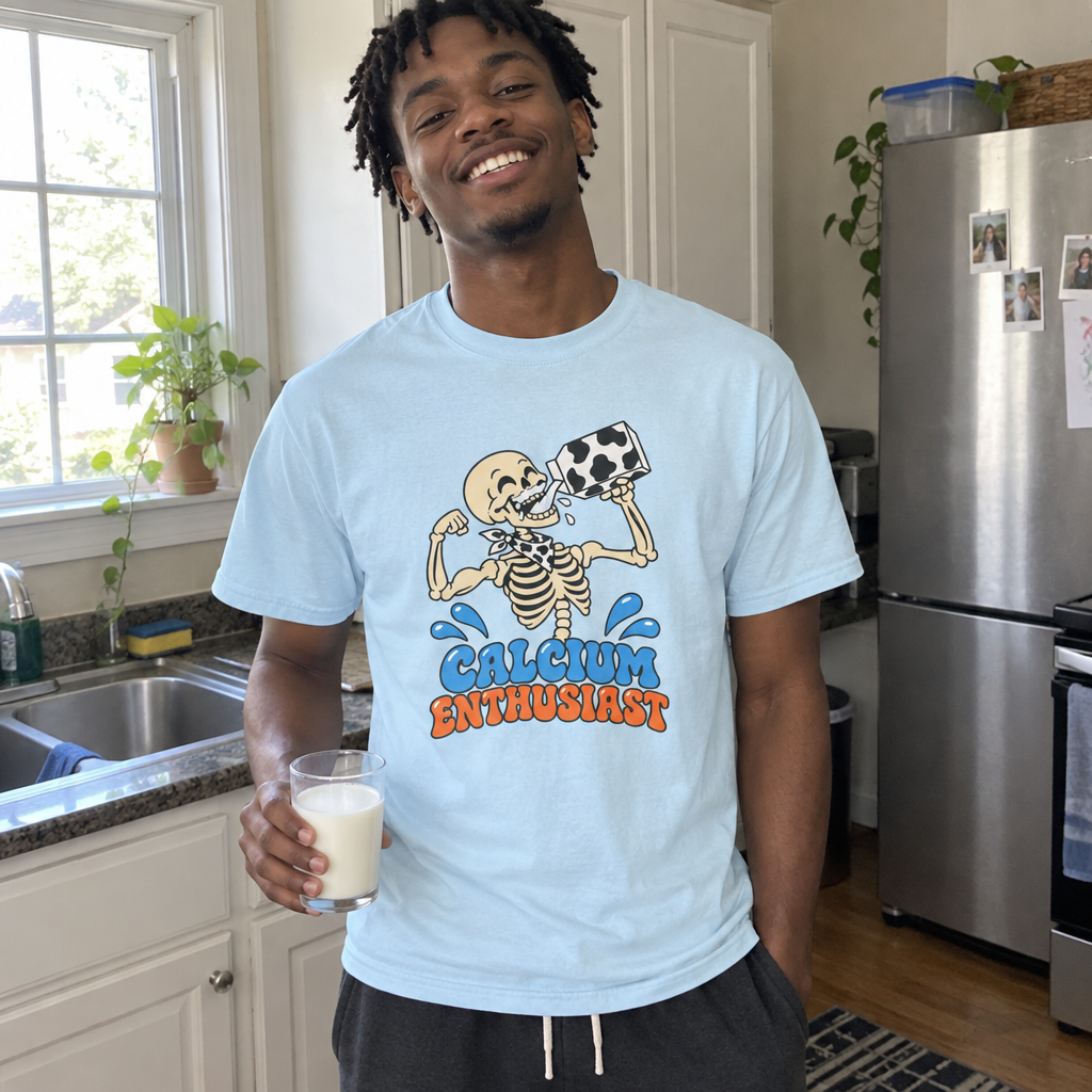 Man wearing the light blue Calcium Enthusiast t-shirt in his kitchen with a glass of milk