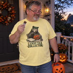 Man wearing the butter yellow Candy Tax Collector t-shirt on a Halloween porch at dusk