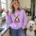 Woman wearing the lilac Bougie Little Vampire sweatshirt sipping tea in her kitchen