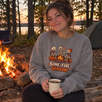 Woman wearing the grey Bone-Fire Season sweatshirt by a campfire
