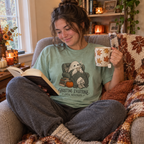 Woman wearing the Ghosting Everyone Until November T-Shirt with a book and tea