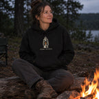 Woman wearing the Light the Way hoodie by a campfire at night