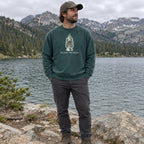 Man wearing the Light the Way crewneck sweatshirt by a mountain lake