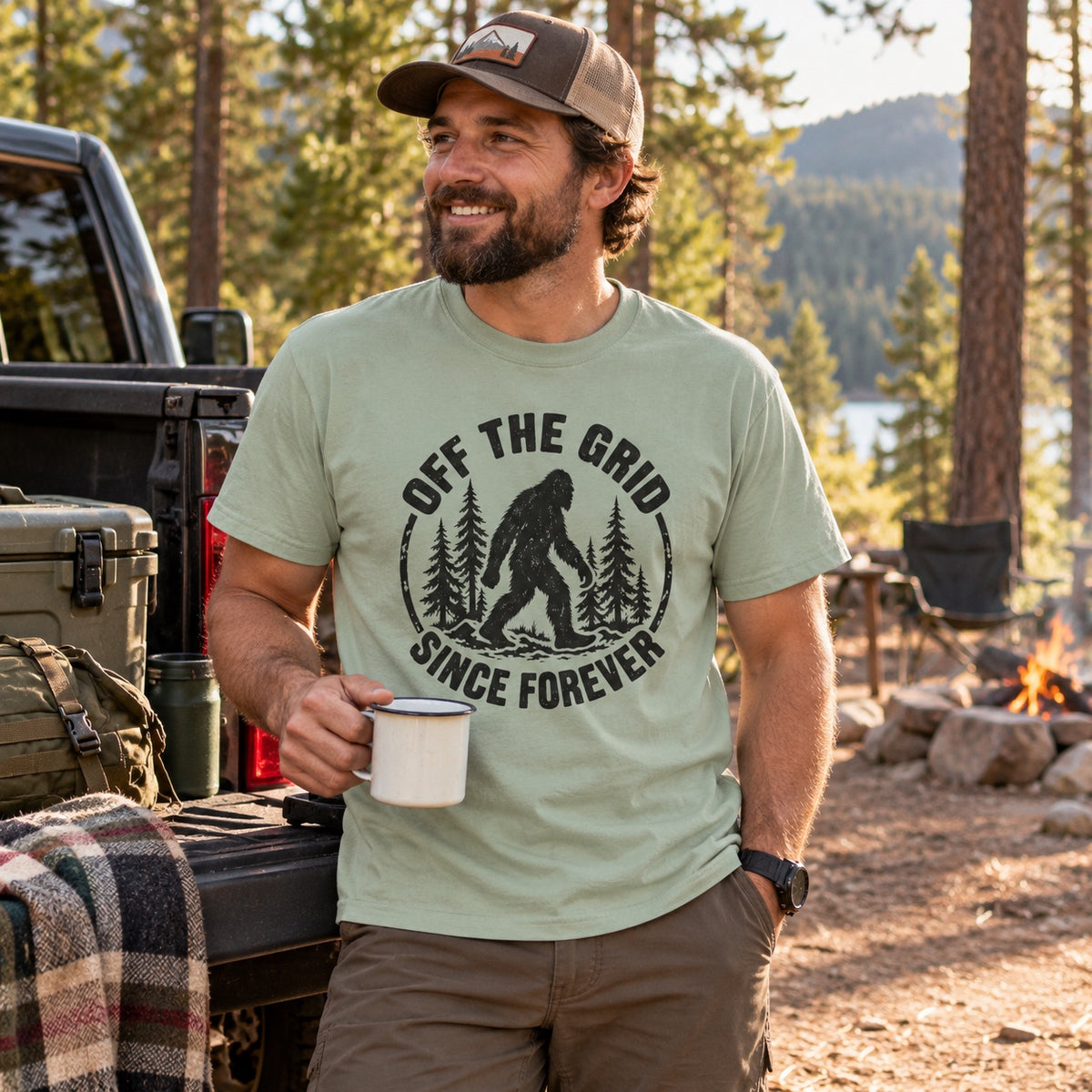 Man wearing the Off the Grid Since Forever Bigfoot t-shirt at a forest campsite