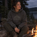 Woman wearing the Take the Long Way hoodie by a campfire at night