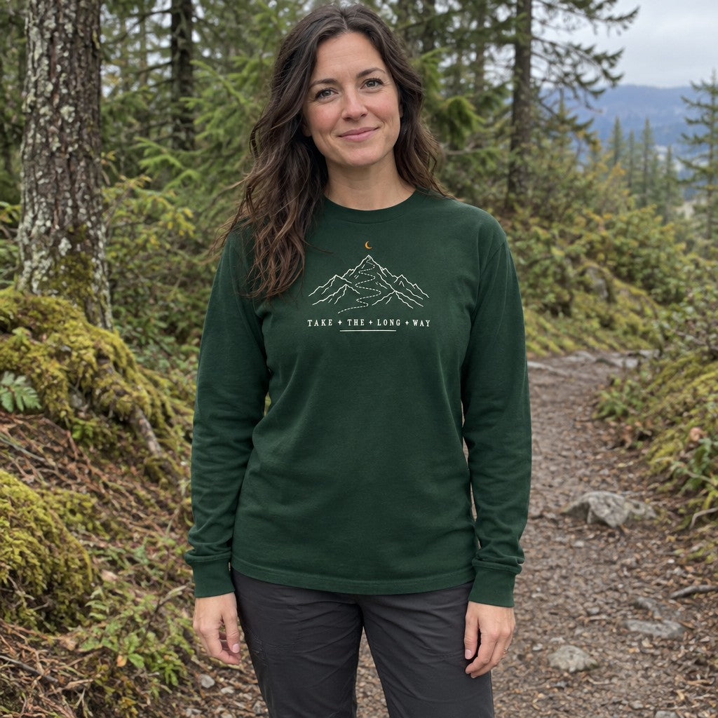 Woman wearing the Take the Long Way long sleeve shirt on a forest trail
