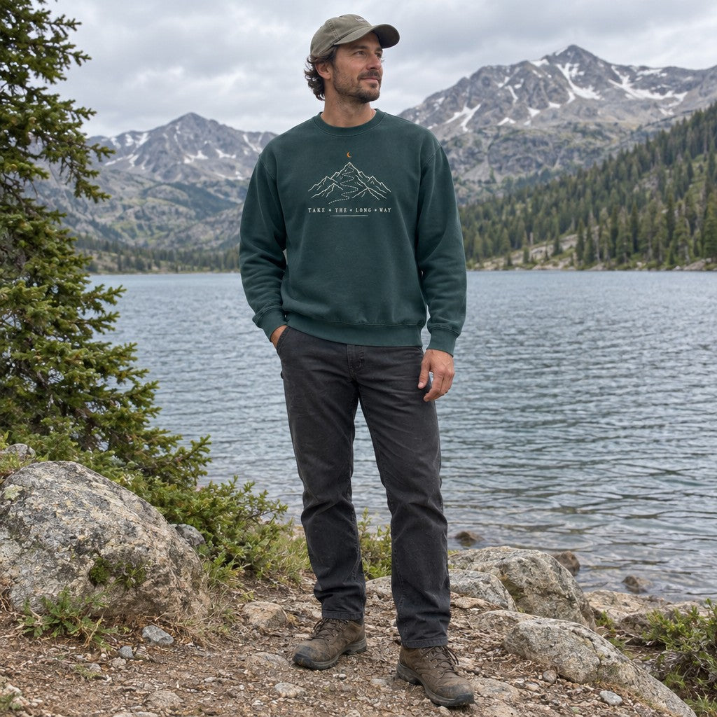 Man wearing the Take the Long Way crewneck sweatshirt by a mountain lake