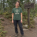 Woman wearing the Lost Signal, Found Trail T-shirt standing at a trail junction sign in the woods