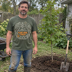 Man wearing the Plant More Trees T-Shirt in Moss next to a new tree