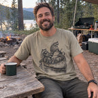Raccoon Canoe Heist T-Shirt worn at a campsite