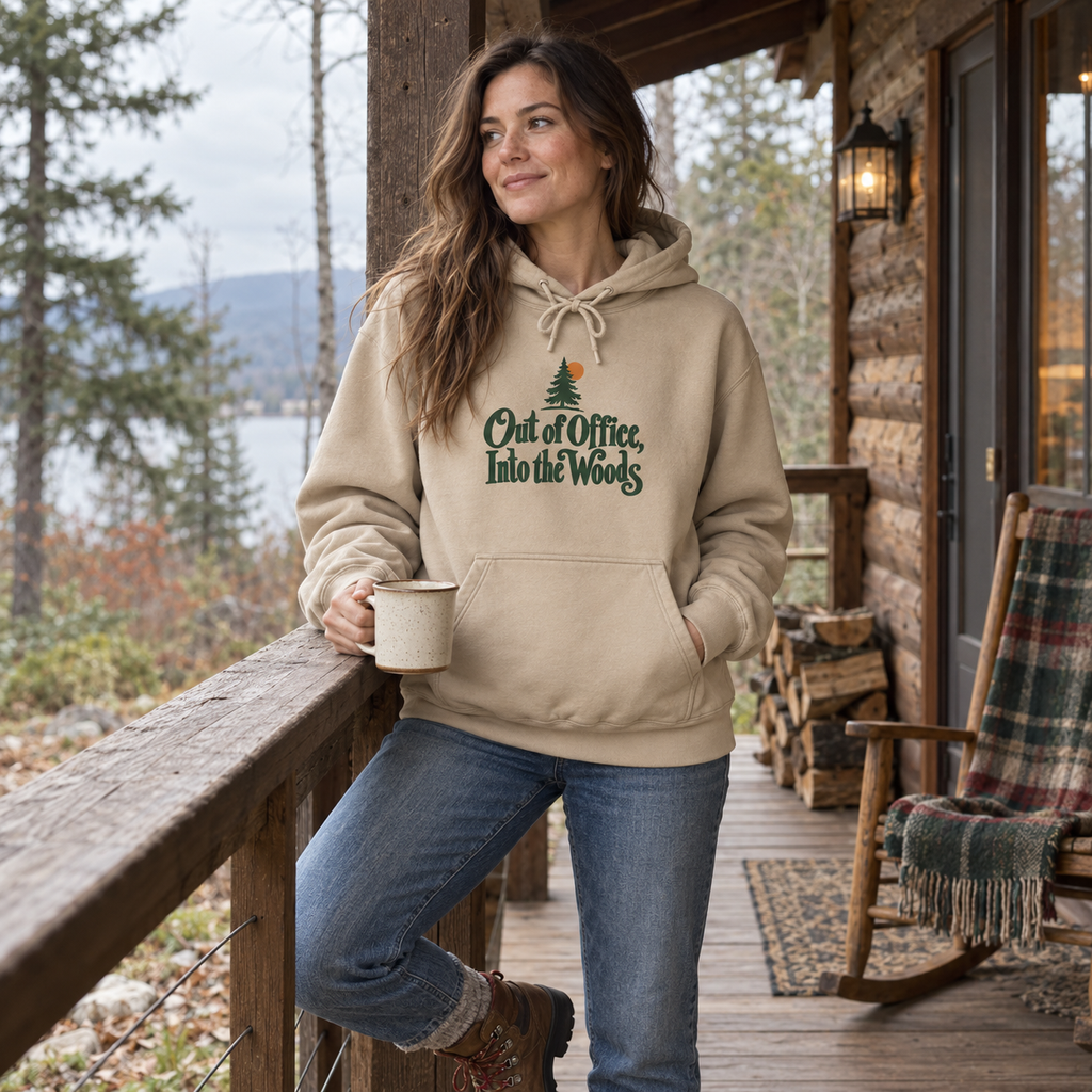 Woman wearing the Out of Office, Into the Woods Hoodie on a cabin porch