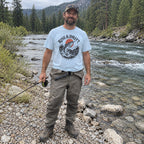 Man wearing the Rise & Drift T-shirt by a river