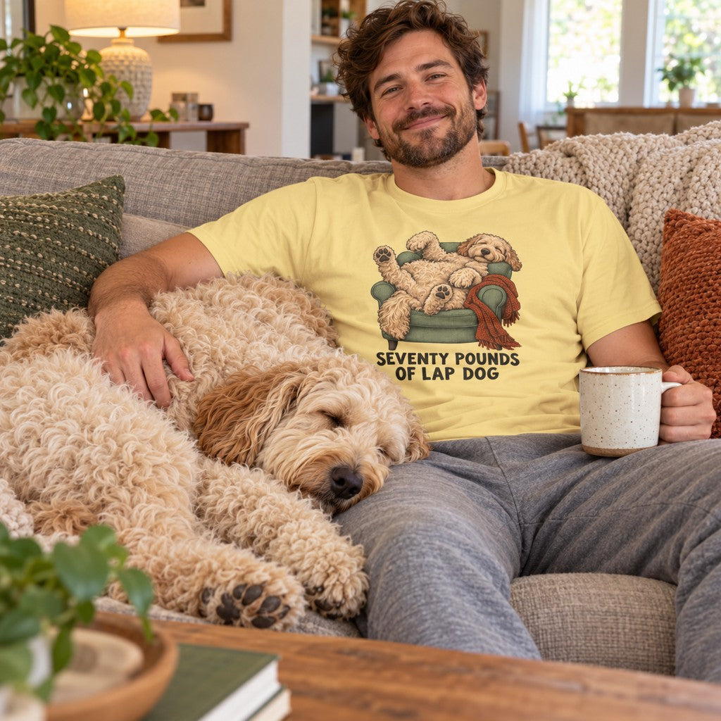Man wearing the Seventy Pounds of Lap Dog T-shirt with a labradoodle asleep on his lap