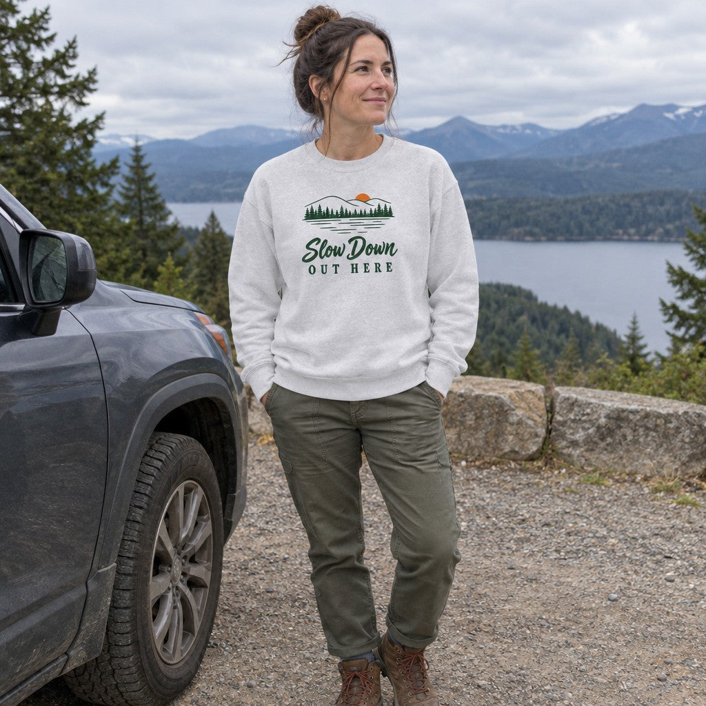 Woman wearing the Slow Down Out Here crewneck sweatshirt at a scenic pull-off by the car