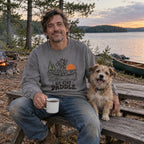 Man at a lakeside campsite wearing the Sit. Stay. Paddle. Sweatshirt with his dog