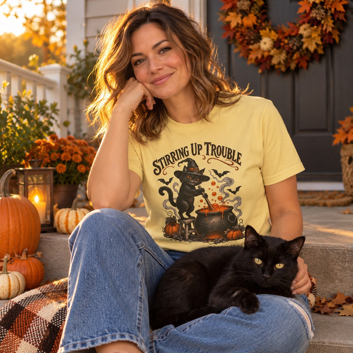 Woman on a porch with her black cat wearing the Stirring Up Trouble T-Shirt