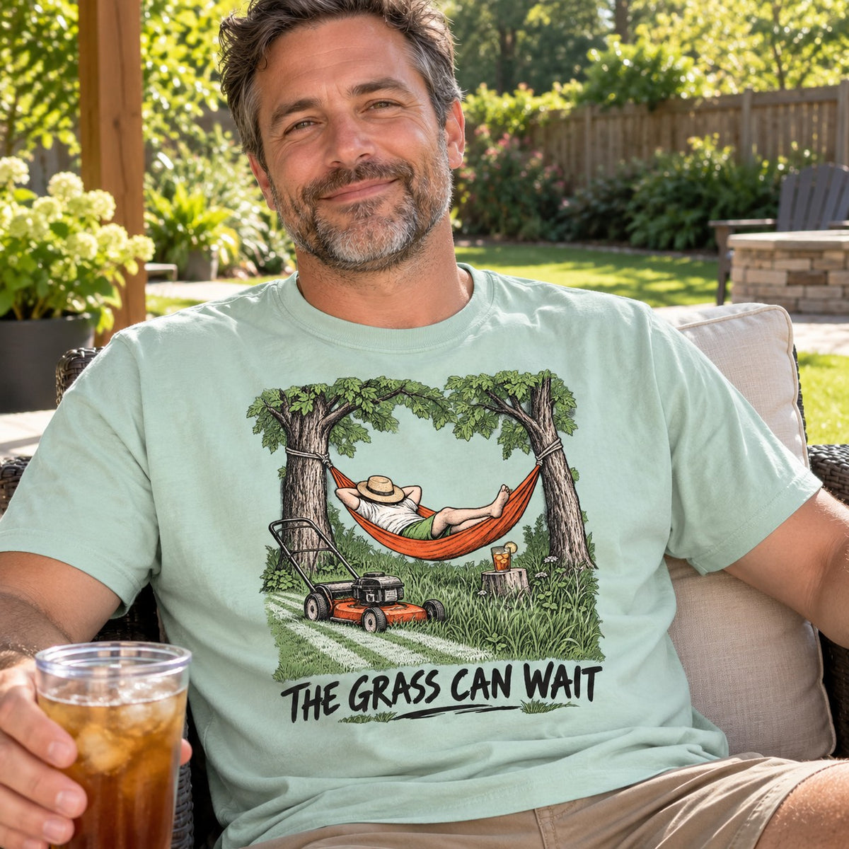 Man relaxing in the backyard wearing The Grass Can Wait T-Shirt in Chalky Mint