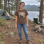 Woman wearing the Topo Pines T-Shirt at a lakeside campsite