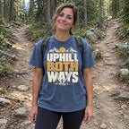 Woman wearing the Uphill Both Ways T-Shirt at a fork in a forest trail