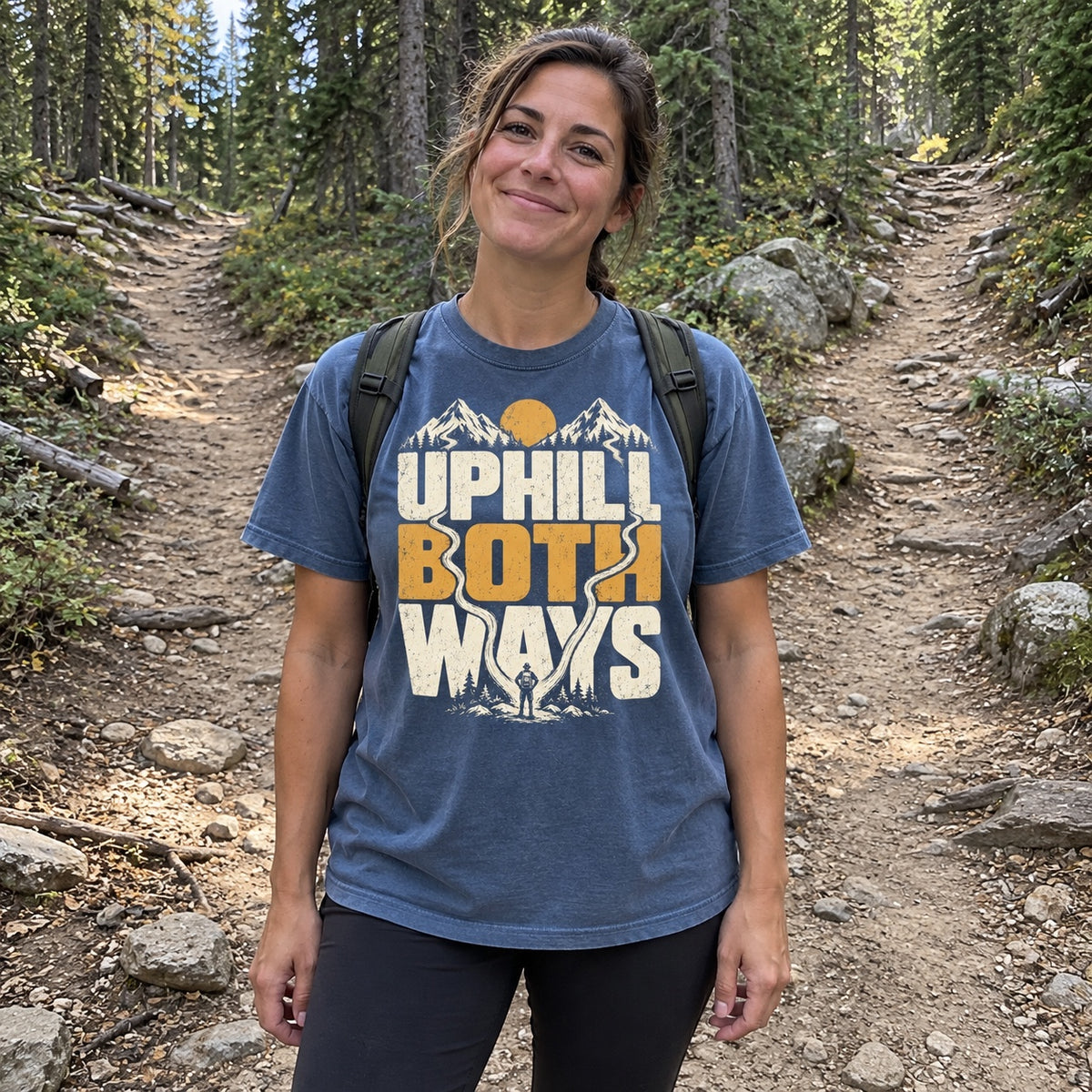 Woman wearing the Uphill Both Ways T-Shirt at a fork in a forest trail