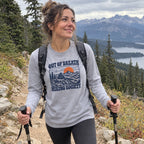 Woman wearing the Out of Breath Hiking Society Summit Rest Long Sleeve Shirt hiking with trekking poles on a mountain trail