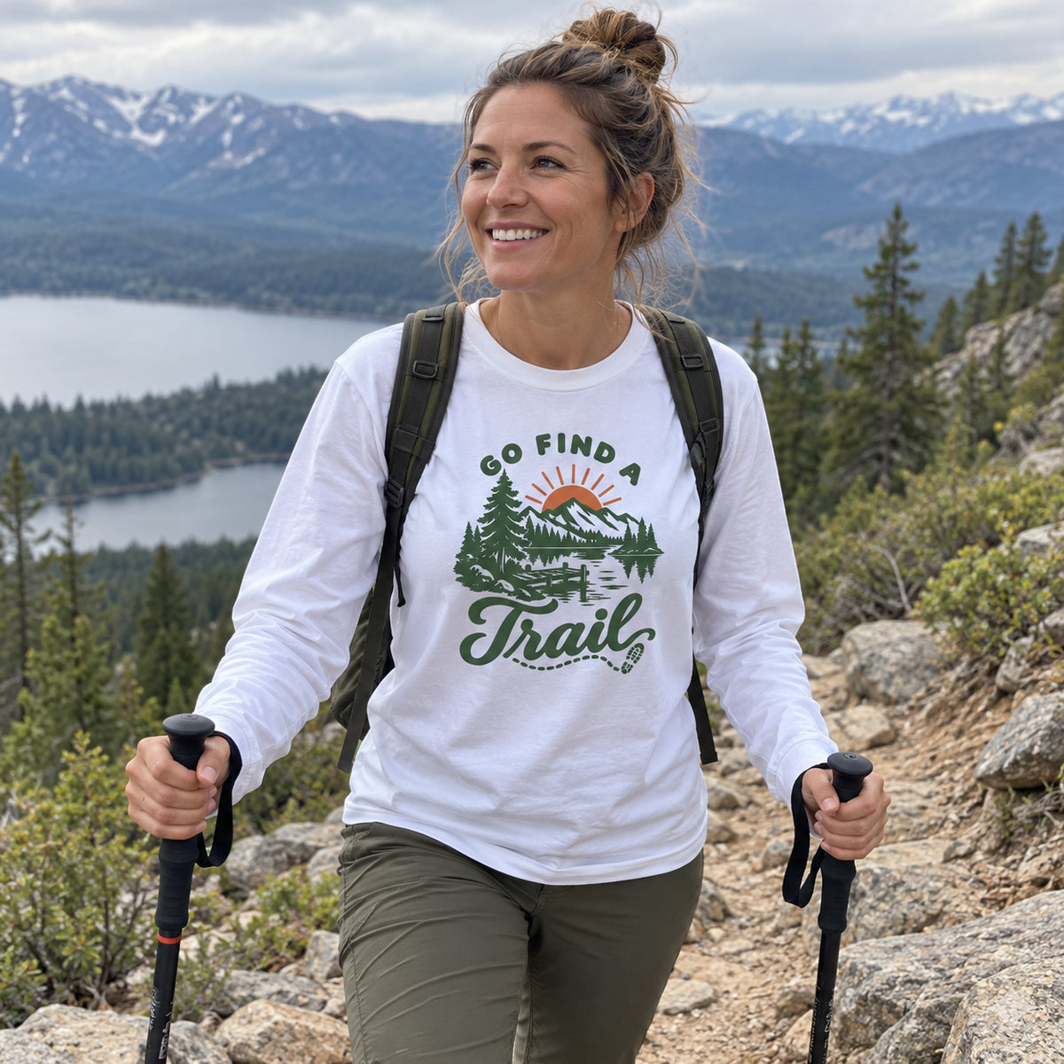 Woman wearing the Go Find a Trail Long Sleeve Shirt hiking with trekking poles on a mountain trail