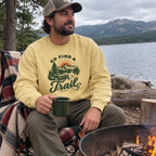 Man wearing the Go Find a Trail Sweatshirt by a lakeside fire pit with a blanket
