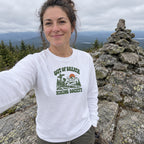 Woman wearing the Out of Breath Hiking Society Trail Sign Long Sleeve Shirt taking a selfie by a summit cairn