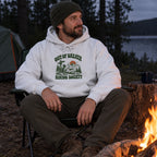 Man wearing the Out of Breath Hiking Society Trail Sign Hoodie by a campfire at night