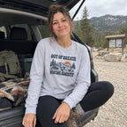 Woman wearing the Out of Breath Hiking Society Flat Out Long Sleeve Shirt at the open back of a car at a trailhead