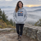 Woman wearing the Out of Breath Hiking Society Summit Rest Hoodie at a misty sunrise overlook