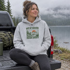 Woman wearing the Out of Breath Hiking Society Sunset Hoodie on a truck tailgate by a misty lake