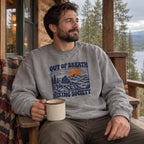 Man wearing the Out of Breath Hiking Society Summit Rest Sweatshirt on a cabin porch with a mug