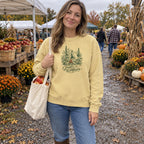 Woman wearing the Campfire & Wildflowers Sweatshirt at a fall farmers market with a bag of apples
